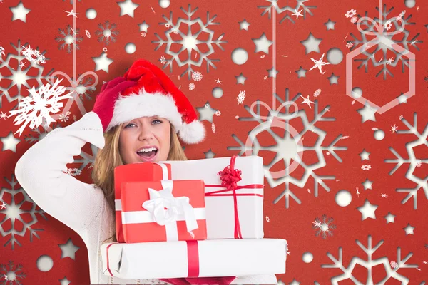 Zusammengesetztes Bild einer festlichen Blondine, die einen Haufen Geschenke in der Hand hält — Stockfoto