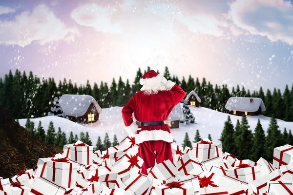 Složený obraz santa stojícího na hromadu dárků — Stock fotografie