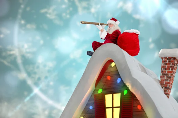 Composite image of santa sitting on roof of cottage — Stock Photo, Image