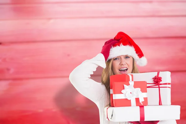 Samengestelde afbeelding van feestelijke blonde bedrijf stapel geschenken — Stockfoto