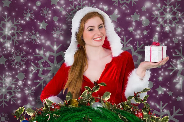 Composite image of pretty girl in santa costume holding gift box — Stock Photo, Image