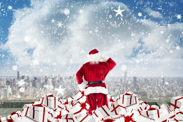 Composite image of santa standing on pile of gifts — Stock Photo, Image