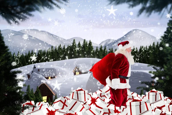 Imagem composta de Papai Noel andando sobre pilha de presentes — Fotografia de Stock