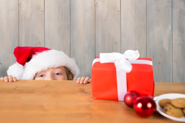 Imagem composta de menino festivo espreitando sobre a mesa — Fotografia de Stock