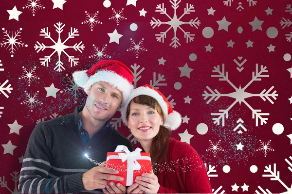 Zusammengesetztes Bild eines Paares mit einem Weihnachtsgeschenk — Stockfoto