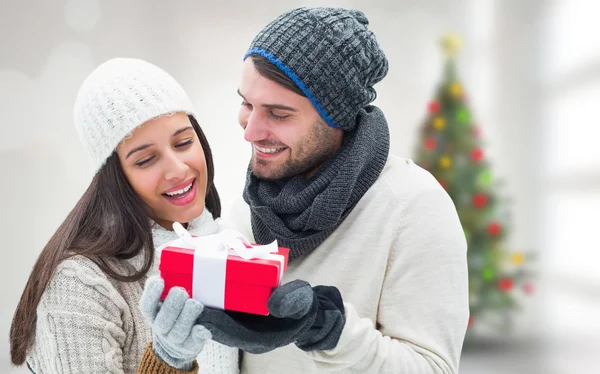 Imagem composta de casal de inverno segurando presente — Fotografia de Stock