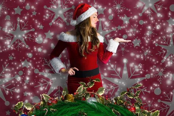 Composite image of pretty girl in santa costume holding hand out — Stock Photo, Image