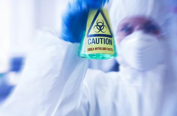 Scientist in protective suit holding beaker — Stock Photo, Image