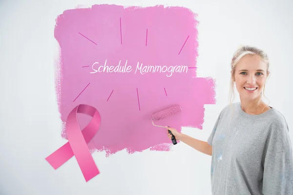 Composite image of happy young woman painting her wall pink — Stock Photo, Image