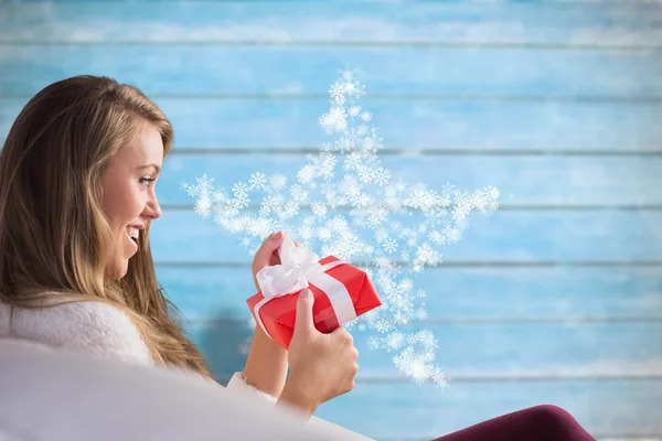 Vackra blonda avkopplande i soffan med gåva — Stockfoto