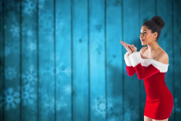 Imagen compuesta de la bonita chica santa soplando sobre sus manos — Foto de Stock