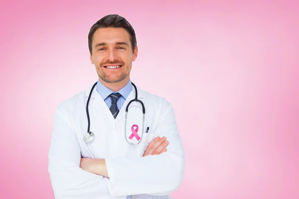 Composite image of handsome young doctor with arms crossed — Stock Photo, Image