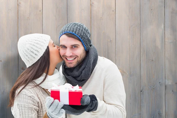 Zusammengesetztes Bild eines Winterpärchens mit Geschenk — Stockfoto