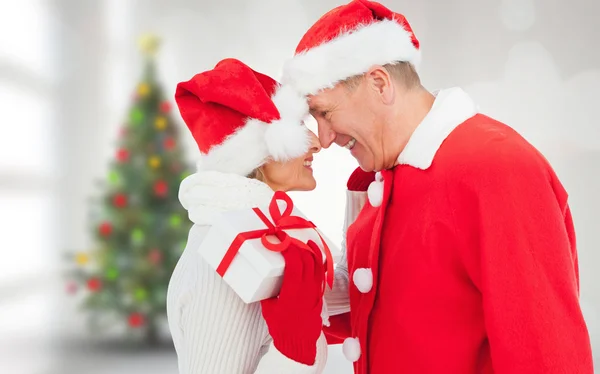 Imagen compuesta de pareja madura festiva sosteniendo regalo —  Fotos de Stock