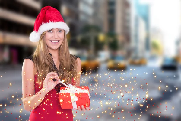 Image composite de blonde festive ouvrant un cadeau — Photo