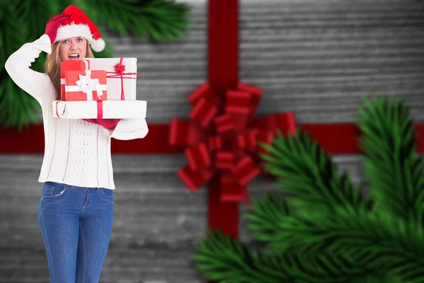 Zusammengesetztes Bild einer festlichen Blondine, die einen Haufen Geschenke in der Hand hält — Stockfoto