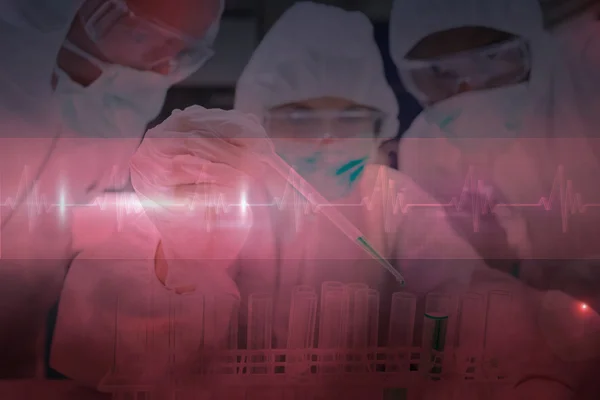 Chemists adding green liquid to test tubes — Stock Photo, Image