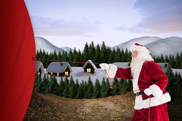 Imagem composta de Papai Noel puxa algo com uma corda — Fotografia de Stock