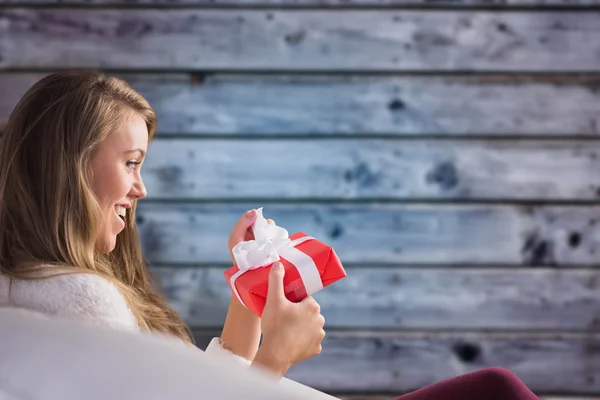 Hübsche Blondine entspannt auf der Couch mit Geschenk — Stockfoto