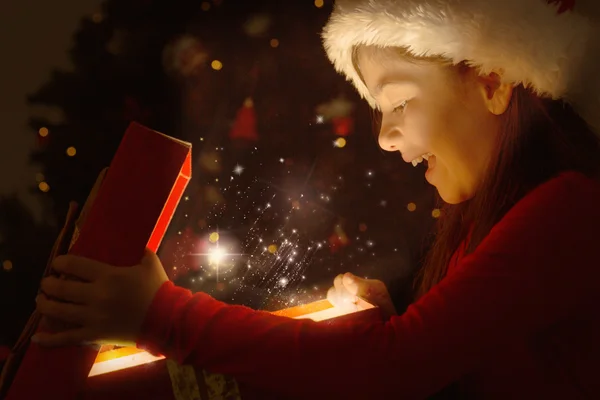 Imagem composta de menina abrindo um presente de Natal mágico — Fotografia de Stock