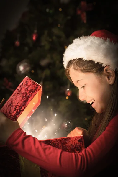 Zusammengesetztes Bild eines kleinen Mädchens beim Öffnen eines magischen Weihnachtsgeschenks — Stockfoto