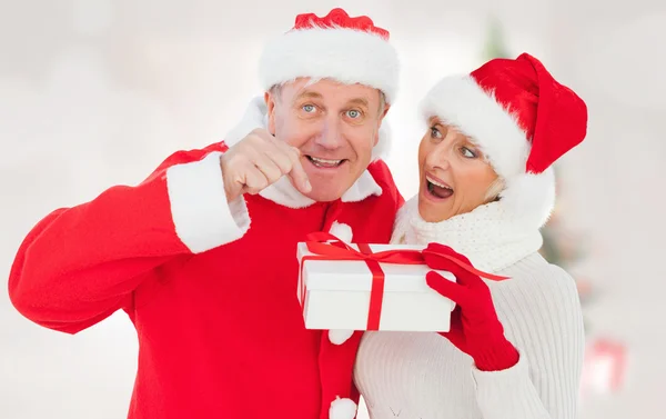 Imagen compuesta de pareja madura festiva sosteniendo regalo — Foto de Stock