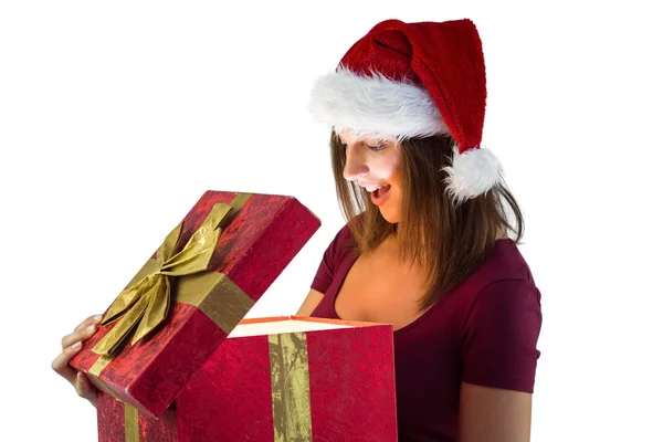 Hübsche Frau mit Weihnachtsmütze öffnet ein Geschenk und lächelt es an — Stockfoto