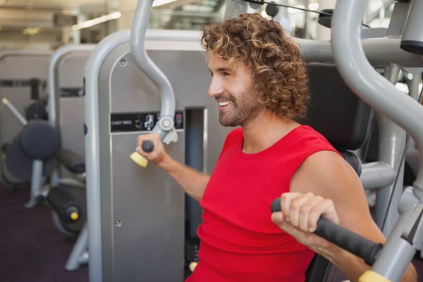 Człowiek pracuje na maszynie fitness w siłowni — Zdjęcie stockowe