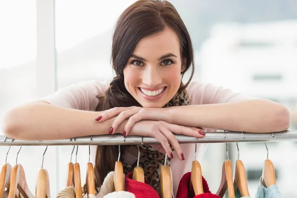 Smiling brunette smiling at camera by clothes rail — Stock Photo, Image