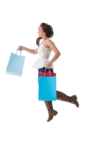 Happy brunette leaping with shopping bags — Stock Photo, Image