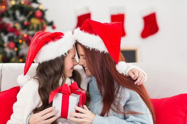 Festiva madre e hija en el sofá con regalo —  Fotos de Stock