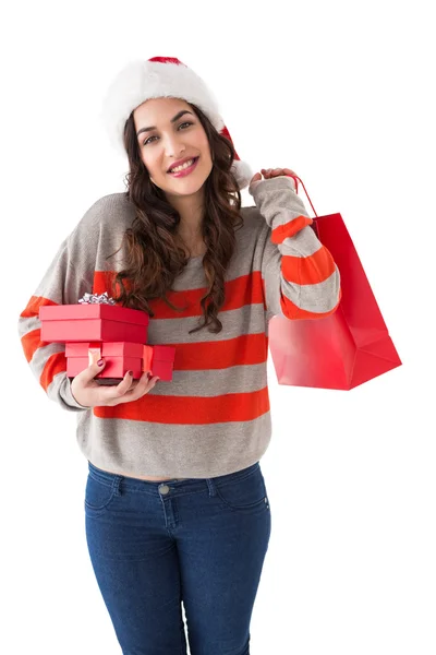 Smiling brunette holding gifts and showing shopping bag — Stock Photo, Image