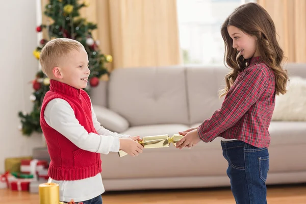 Feestelijke broers en zussen trekken een cracker — Stockfoto