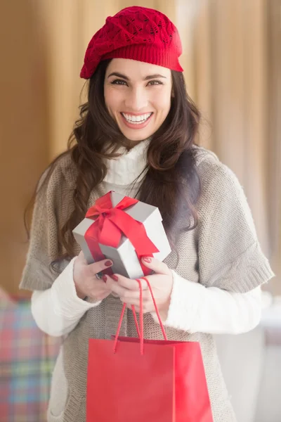 Feliz morena sosteniendo regalo y bolsas de compras — Foto de Stock