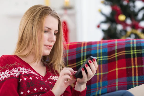 Pretty blonde sitting on the couch texting on the phone — Stock Photo, Image