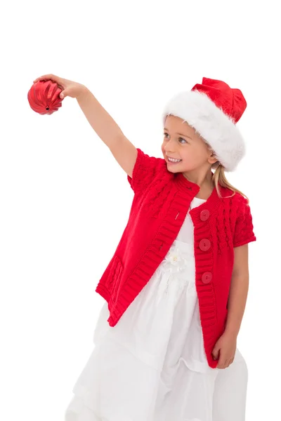 Niedliches kleines Mädchen mit Weihnachtsmütze und Christbaumkugel — Stockfoto