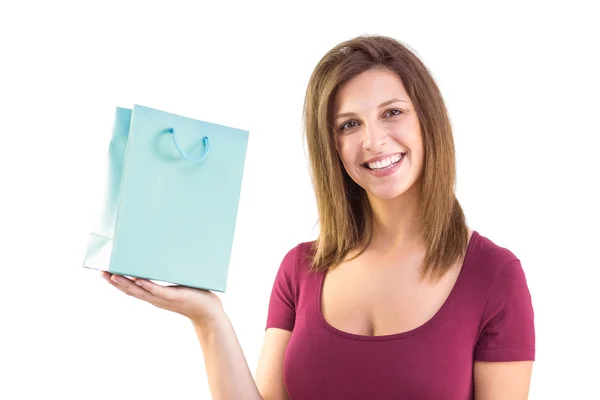 Morena sosteniendo una bolsa de regalo sonriendo a la cámara — Foto de Stock