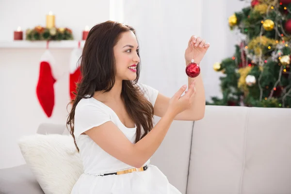 Gelukkig brunette houdt een rood bauble op Kerstmis — Stockfoto