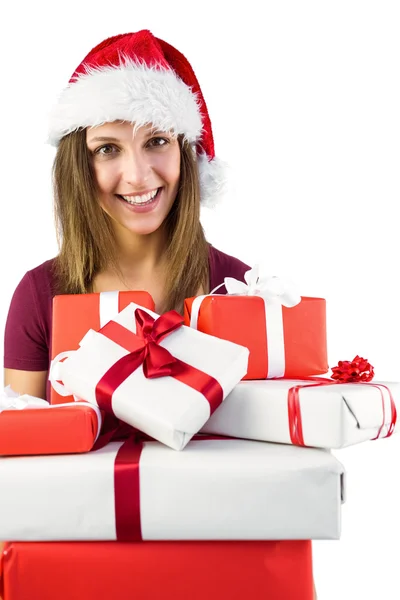 Sonriente morena en santa hat sosteniendo montón de regalos — Foto de Stock