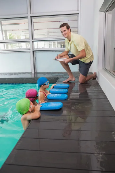 Graziosa classe di nuoto ascoltando allenatore — Foto Stock