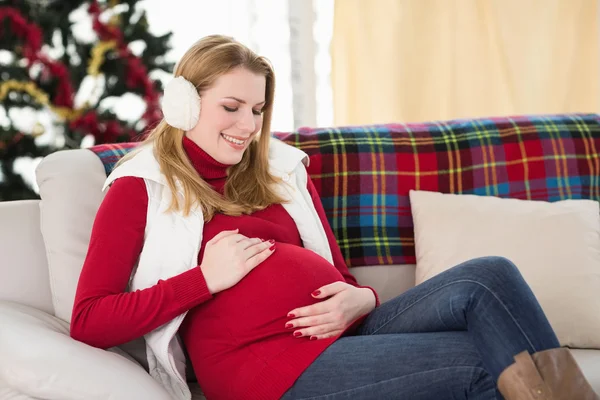 Pregnant woman rubbing her belly on the couch — Stock Photo, Image