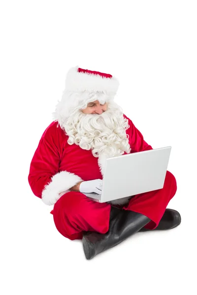 Weihnachtsmann sitzt und benutzt seinen Laptop — Stockfoto