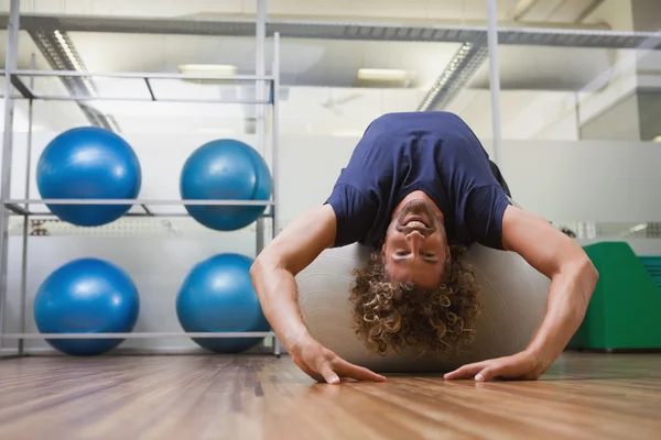 Man die zich uitstrekt over fitness bal in gym — Stockfoto