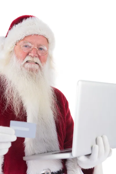 Santa paga con tarjeta de crédito en un ordenador portátil —  Fotos de Stock