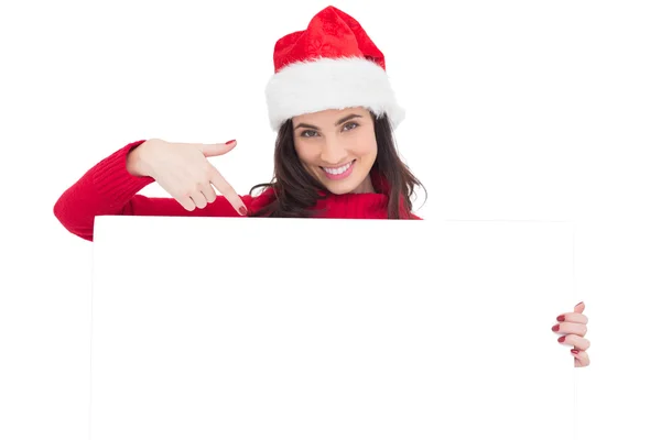 Pretty brunette in santa hat pointing white poster — Stock Photo, Image