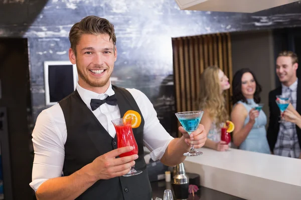 Kokteyller tutan kameraya gülümseyen yakışıklı barmen — Stok fotoğraf