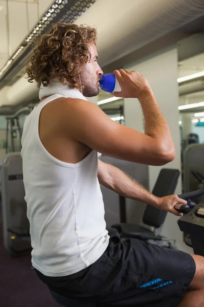 Hombre beber agua en bicicleta estática — Foto de Stock