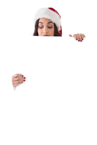 Skönhet brunett i santa hatt visar vit affisch — Stockfoto