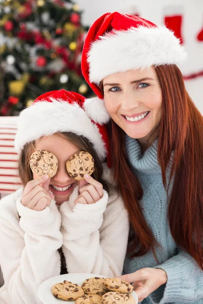 Праздничные мать и дочь на диване с печеньем — стоковое фото