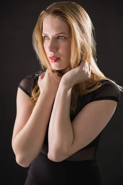 Blonde model in black dress posing looking away — Stock Photo, Image